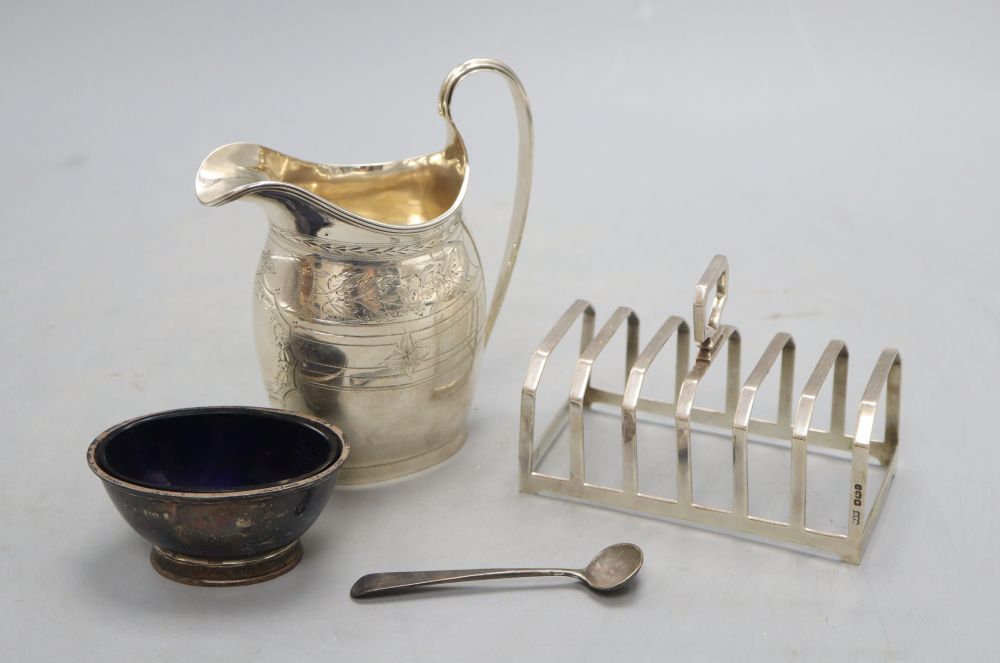 An Edwardian silver milk jug, 13.3cm, a silver toast rack, silver salt and silver condiment spoon, 9oz.